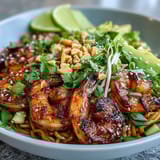 Topped with crisp cucumber, sprouts, and chopped peanuts, this Grilled Shrimp Asian Noodle Bowl glistens with a savory sesame glaze.