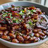 Golden-brown bacon crumbles top a thick, sweet, and savory bean casserole fresh from the oven.  