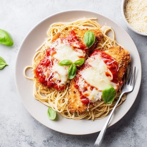 Fresh basil garnish and grated Parmesan top this classic Chicken Parmesan, perfect for a cozy weeknight dinner.