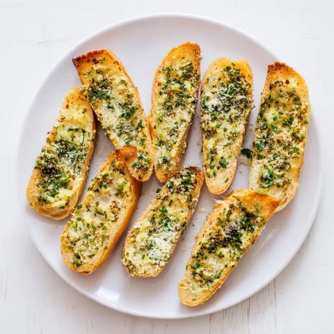 Freshly baked Garlic Bread with herb-flecked butter melting into the crusty bread edges.