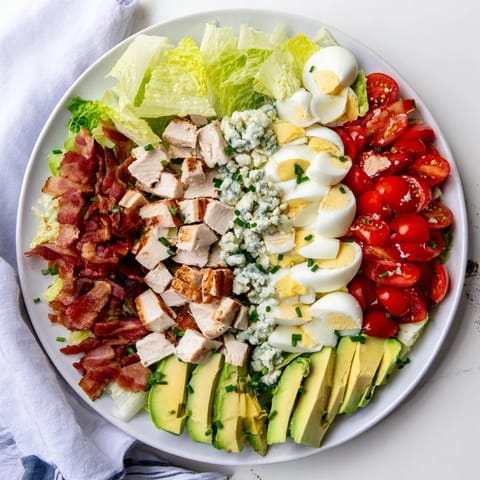 Colorful Cobb Salad topped with hard-boiled eggs, diced tomatoes, and tangy blue cheese, ready to serve.