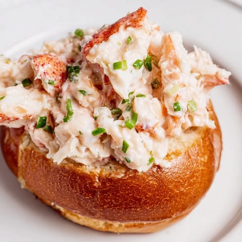 Generous New England Lobster Roll filling with tender lobster meat and chives on a buttery toasted bun.
