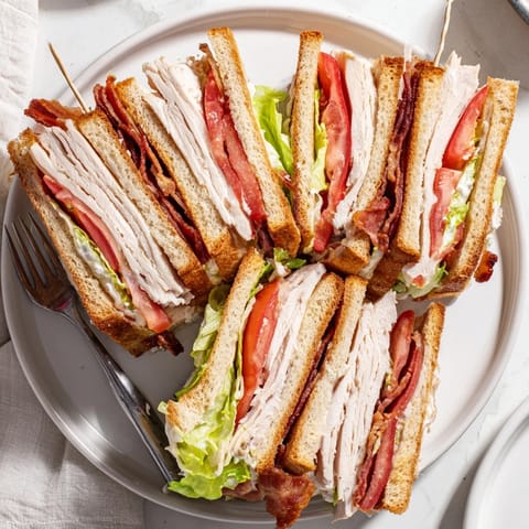Perfectly stacked triple-decker Turkey Club Sandwich served with crunchy potato chips and tangy dill pickles on the side.