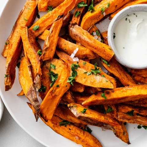 Sweet Potato Fries seasoned with paprika and sea salt, arranged on a baking sheet fresh from the oven.