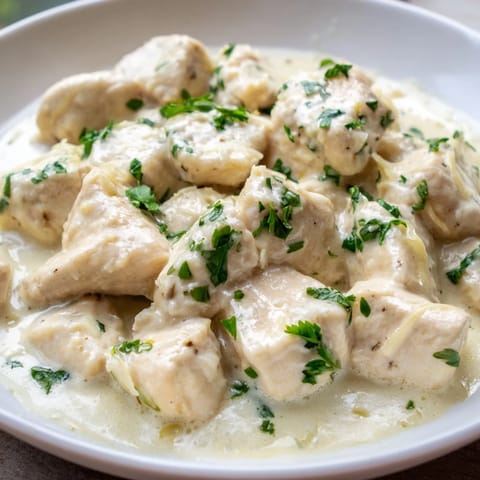 Tender Creamy Garlic Chicken Bites coated in rich, Parmesan-infused sauce, garnished with fresh parsley and served hot.