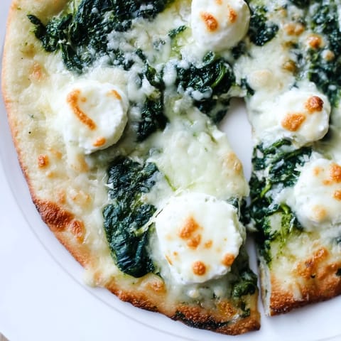 Spinach Ricotta Pizza sliced into wedges on a rustic board, ready to serve with a crisp green salad.