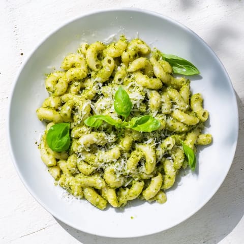 Creamy Avocado Pesto Mac is served in a white bowl with a lemon wedge on the side.  