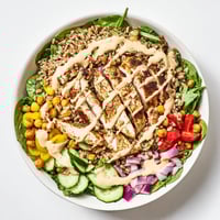 Golden roasted chicken and crispy chickpeas top a bed of farro and greens in this vibrant Lemon Tahini Chicken Power Bowl, ready to serve.